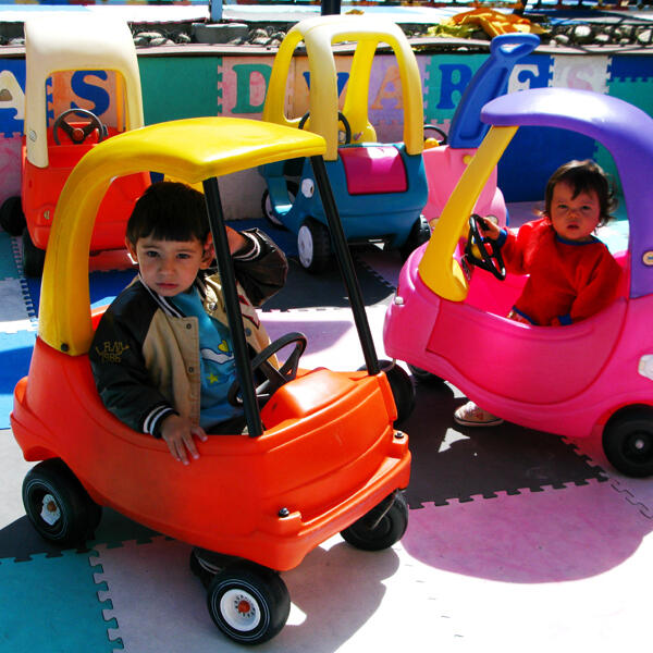 Children riding toy cars outside