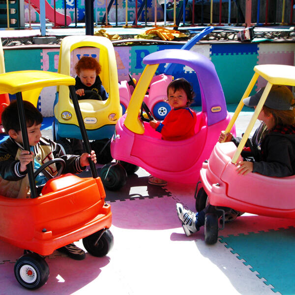 Untitled Children riding toy cars in the outdoor play area