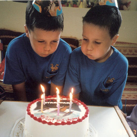 Twin brothers blowing out birthday candles