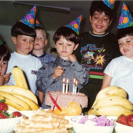Untitled Children celebrating with cake, fruit, and party hats
