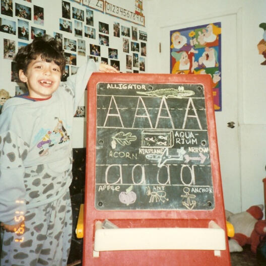 Child learning letters on a chalkboard