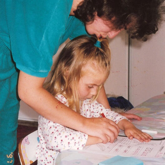 Lana helping a child with writing practice at her San Francisco preschool.
